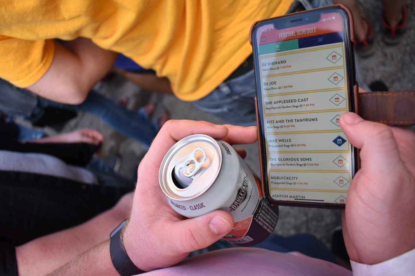 A person using the Boulevardia mobile app, checking out the festival schedule. The app interface is sleek and intuitive, displaying a clear lineup of performances with times and stage locations. 